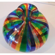 a multicolored glass vase sitting on top of a white table