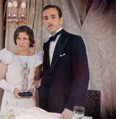 a man in a tuxedo standing next to a woman wearing a white dress