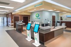 the front desk of a medical office with two monitors on it's sides and an open door leading to another room