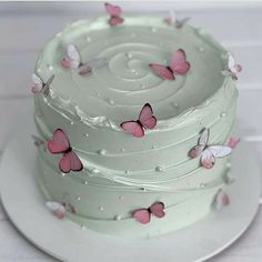 a three layer white cake with pink butterflies on the icing and frosting, sitting on a plate