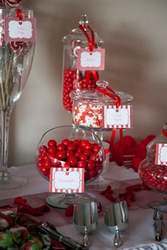 candy bar with red candies in glass vases and place cards on the table