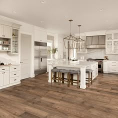 a large kitchen with white cabinets and wood floors