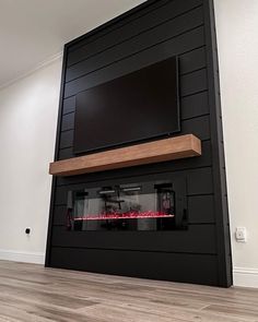 a large television mounted on the wall above a fire place in a room with wood floors