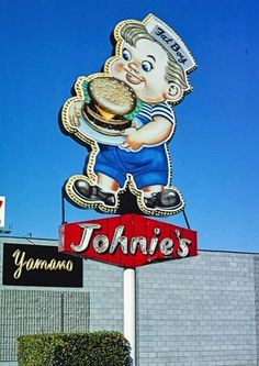 a large sign with a cartoon character holding a hamburger on it's back and the words johnie's written in front