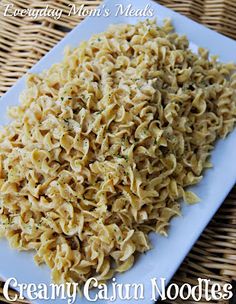 a white plate topped with pasta covered in cheese and seasoning next to a wicker basket