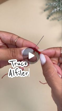 someone is making something with yarn and needles on the table next to a christmas tree