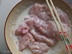 some meat and chopsticks are in a bowl