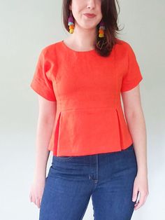 a woman in an orange top is posing for the camera with her hands on her hips