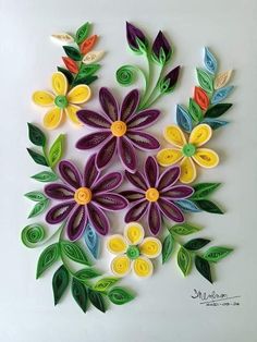 paper flowers are arranged in the shape of leaves and petals on a white surface with green, yellow, purple, and red colors