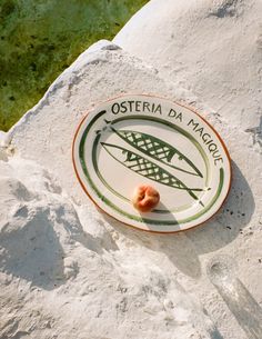 a plate with some food on it sitting in the sand next to a body of water