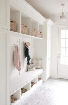 a white coat rack with shoes and hats on it next to a door in a hallway