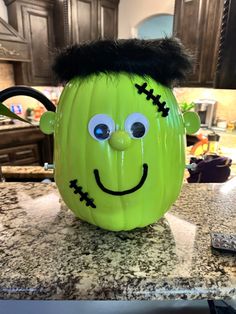 a green halloween pumpkin with a black hair on it's head sitting on top of a kitchen counter