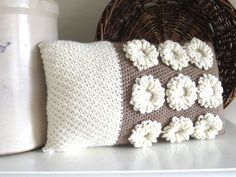 a crocheted pillow sitting on top of a white shelf next to a basket