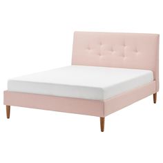 a pink bed with white sheets and wooden legs