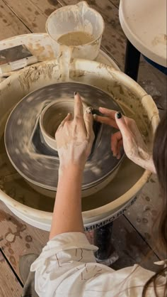 a woman is making something out of clay on a potter's wheel with her hands