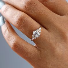 a woman's hand with a diamond ring on top of her finger and an engagement band