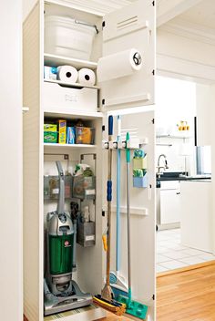 the inside of a white cabinet with cleaning supplies in it and two mop's