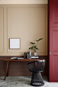 a desk with a plant and some books on it in front of a red door