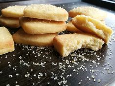 some sugar cookies are on a cutting board with sprinkles and salt scattered around them