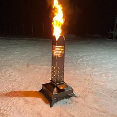 a fire pit sitting on top of a snow covered ground next to a metal object