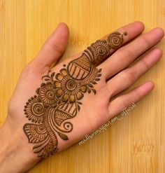 the hand is decorated with henna designs on top of wooden boards and wood flooring