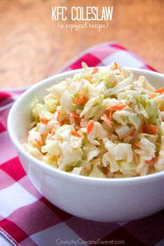 a white bowl filled with coleslaw on top of a checkered table cloth