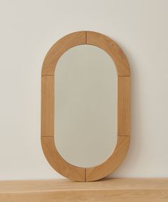 a round mirror sitting on top of a wooden shelf