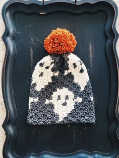 a black and white hat with an orange pom - pom