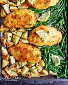 chicken, potatoes and green beans in a baking pan with lemon wedges on the side