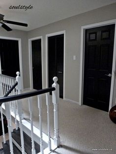 an empty room with black doors and white railings on the second floor is seen in this image