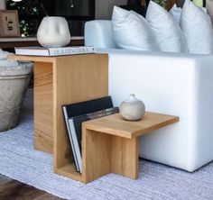 a white couch sitting next to a wooden table with books on it and vases