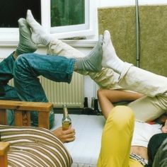 two men laying on the ground with their feet up and one man holding a beer