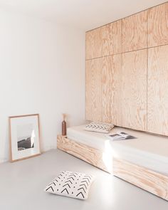 a bed sitting on top of a white floor next to a wooden wall mounted shelf