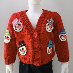 a red sweater with snowmen on the front and two hats on the back, sitting on a mannequin's head