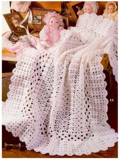 a crocheted blanket and doll are sitting on a chair in front of an old photo