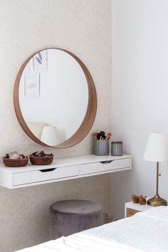 a bedroom with a white dresser, mirror and small stool in front of the bed