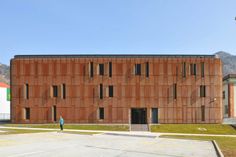 the building is made out of wood and has many windows on each side, along with a man standing in front of it