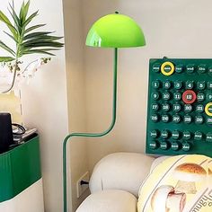 a green lamp sitting on top of a table next to a white couch and chair