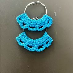 a crocheted keychain hanging from a metal hook on a black surface