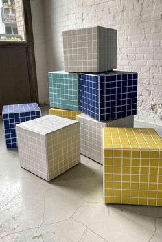 four different colored cubes sitting next to each other in front of a brick wall