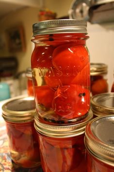 jars filled with tomatoes sitting on top of a counter