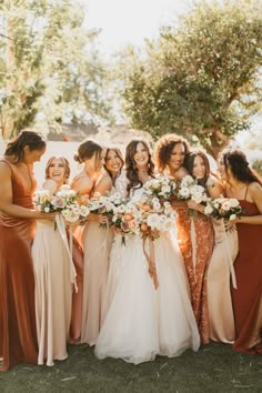 a group of women standing next to each other holding bouquets in their hands and smiling