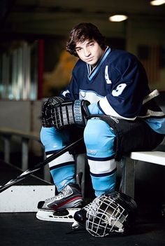 a young man sitting on top of a bench wearing an ice hockey uniform