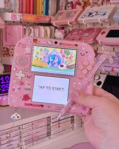 a person holding up a pink nintendo wii game controller in front of a store display