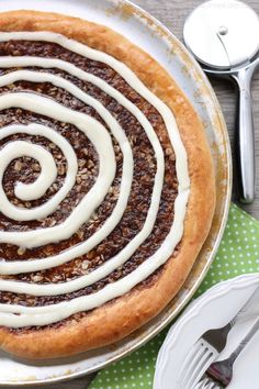 a cinnamon roll with icing on a plate next to silverware and utensils