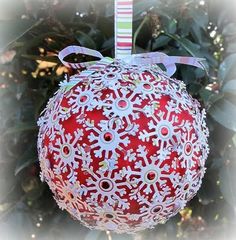 a red ornament hanging from a tree with a ribbon on it's end