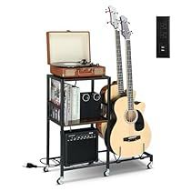 a guitar stands next to a record player and other musical instruments on a stand with wheels