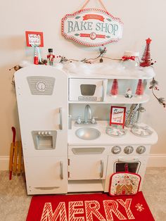 a white toy oven sitting on top of a red rug next to a christmas sign