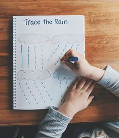 a child's hand writing on a piece of paper that says trace the rain