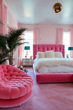 a bedroom decorated in pink and white with a round bed, two couches and a plant